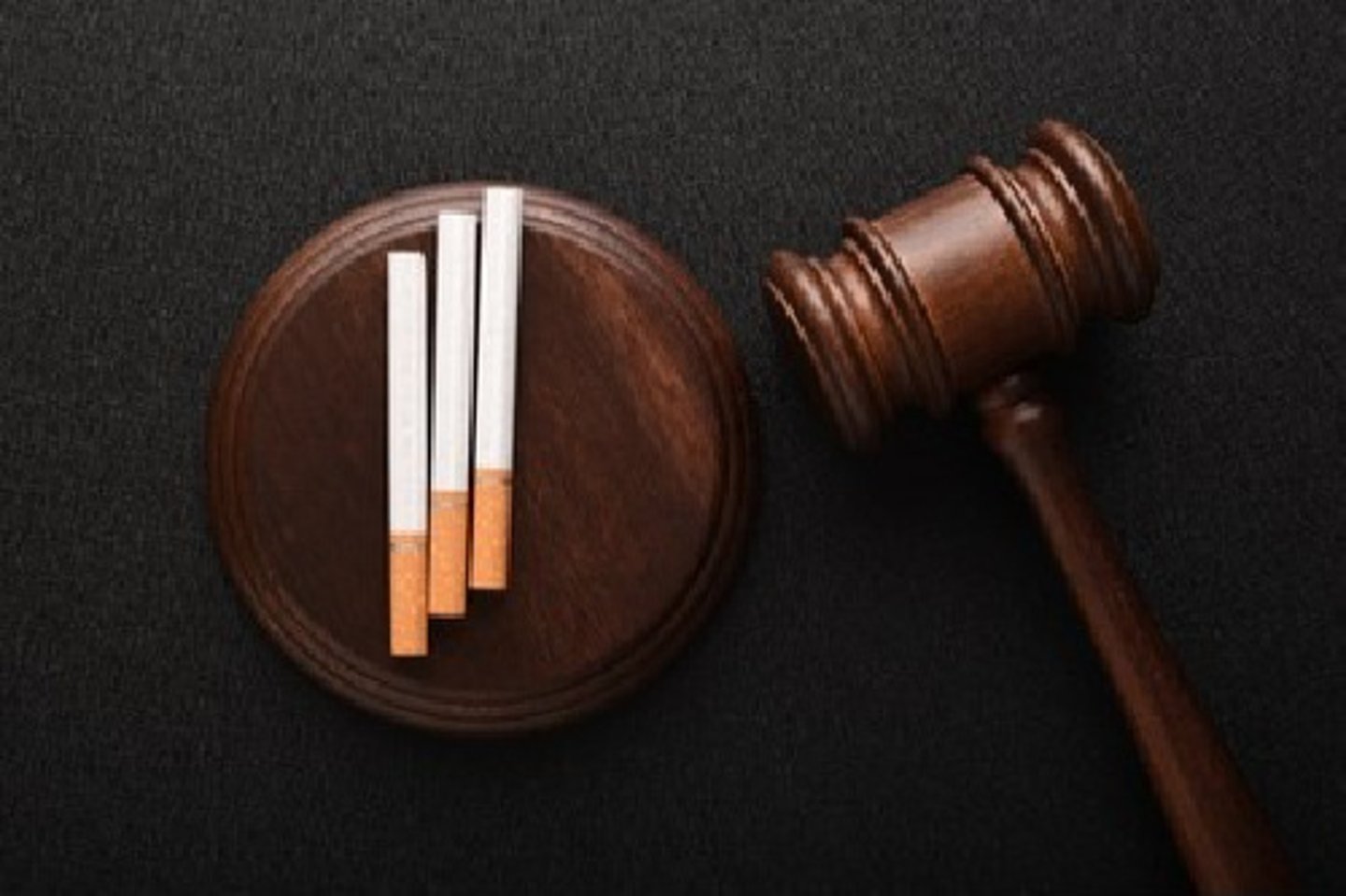 Cigarettes and wooden Judge gavel top view on black background. Violation of the terms of sale of tobacco. Tobacco law