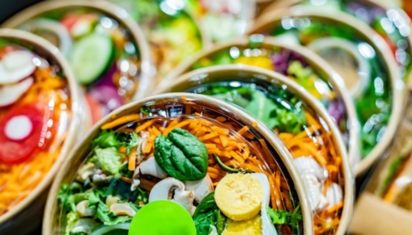 Pre-packaged vegetable salads displayed in a commercial refrigerator