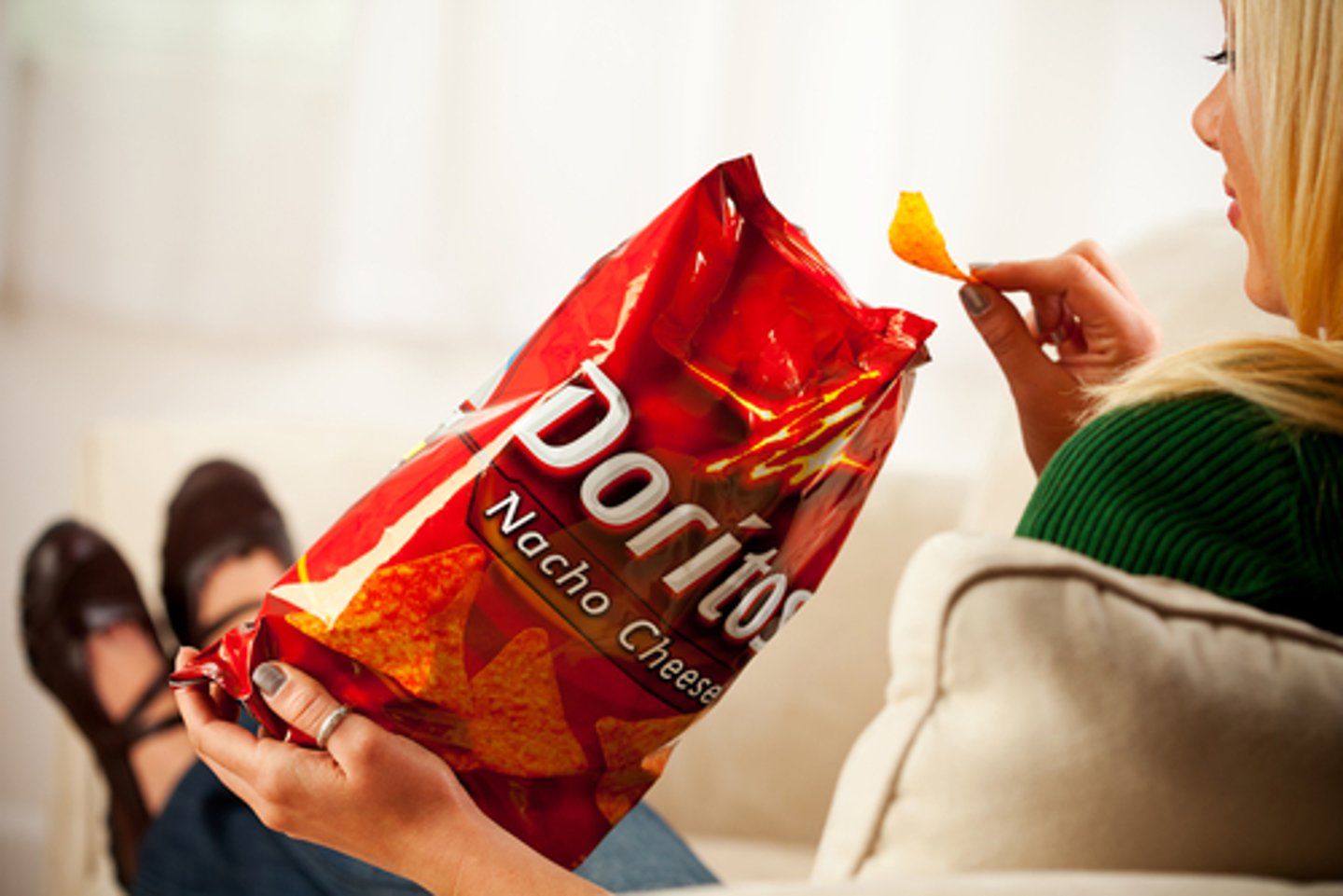 Woman Eats Chip From Bag Of Doritos, Produced By The Frito Lay Company.