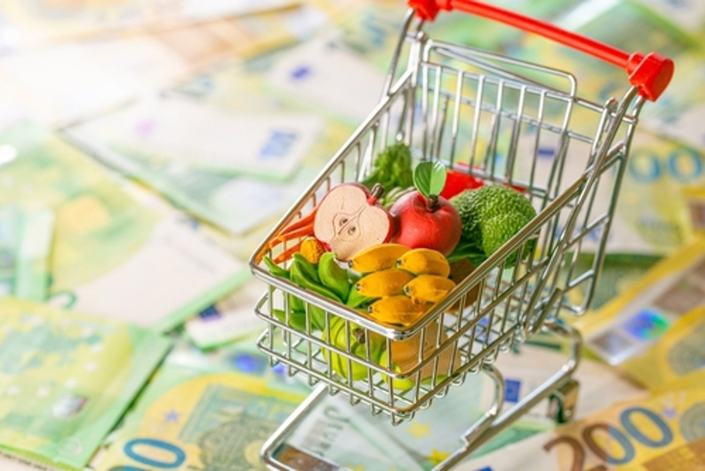 ecorative supermarket trolley with groceries on euro banknotes background.Grocery basket in Europe. food crisis.