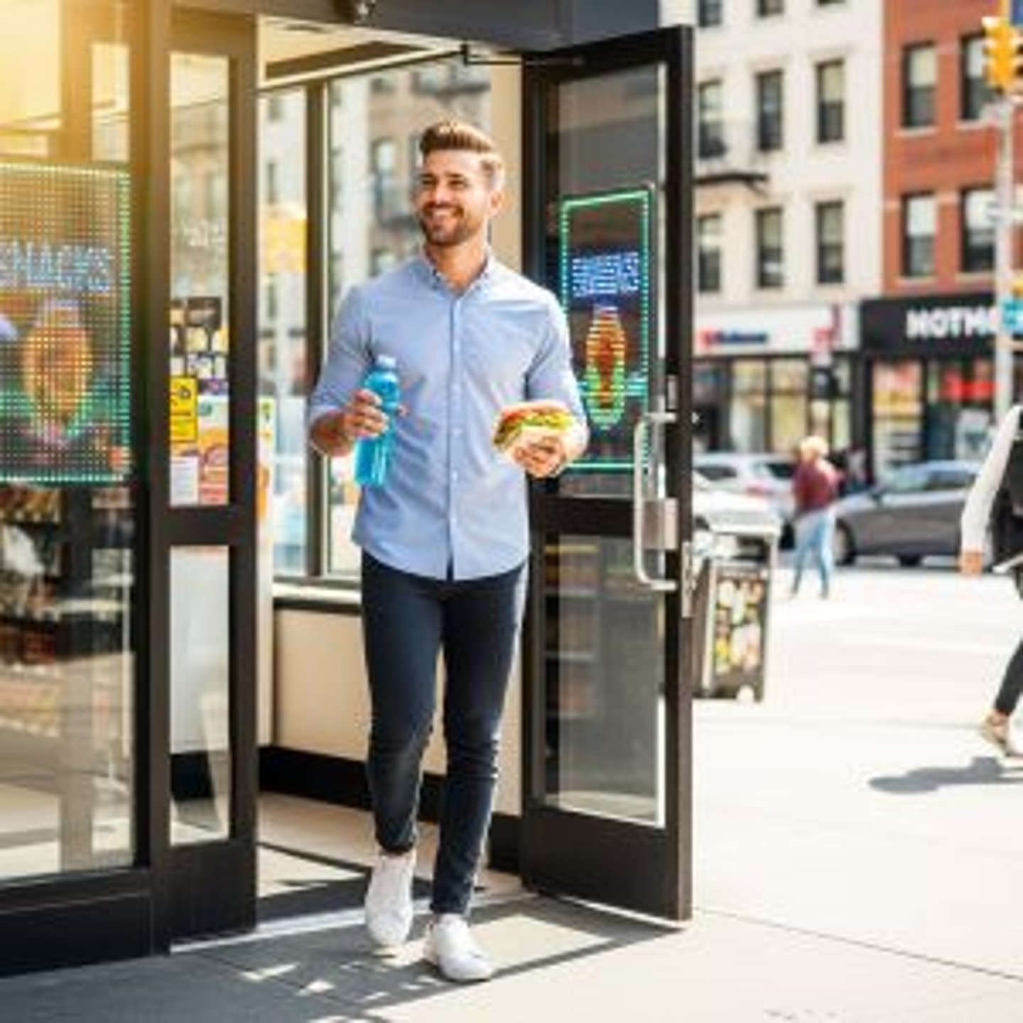 Man with food exiting a convenience store stock image
