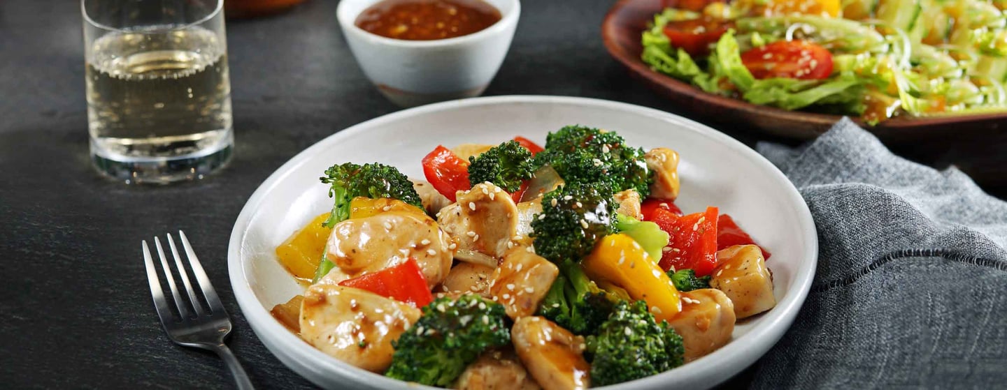 Sesame stirfry plated with chicken and broccoli on nicely set table