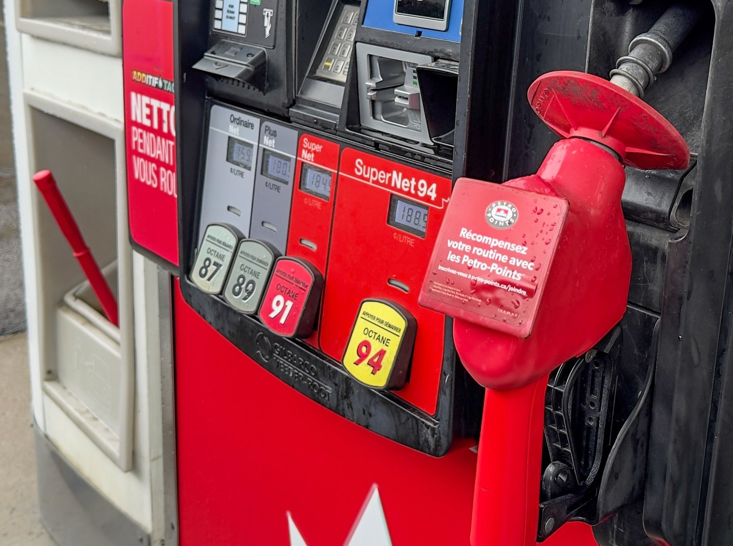 close up red gas pump showing fuel grades