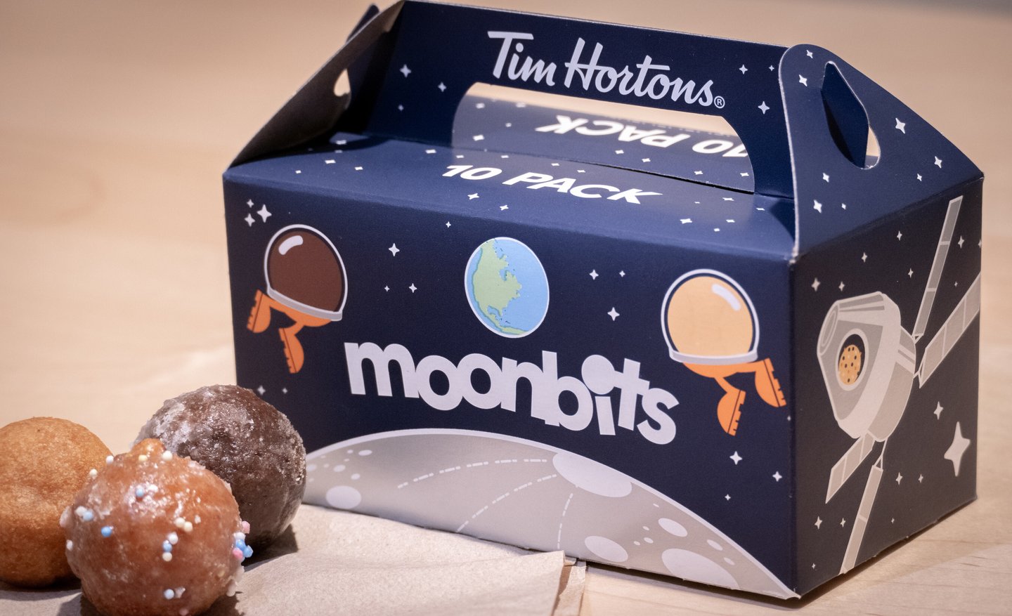 Box of Tim Hortons "Moon bits" box with a few Timbits in front of it.