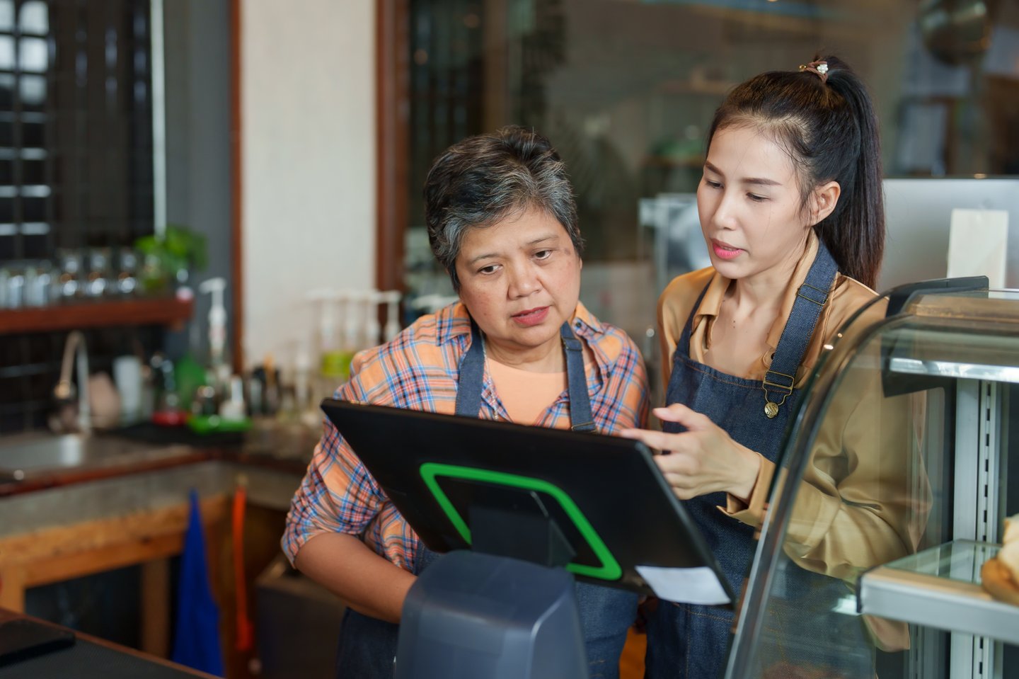 Two women working together at till at coffee or other shop
