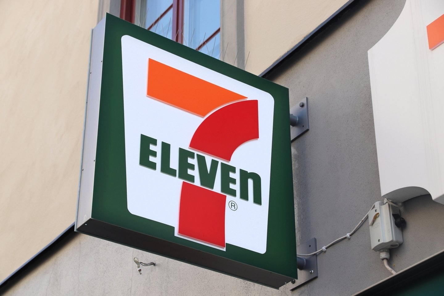 Close up of exterior of an unlit 7-Eleven neon sign in the day.