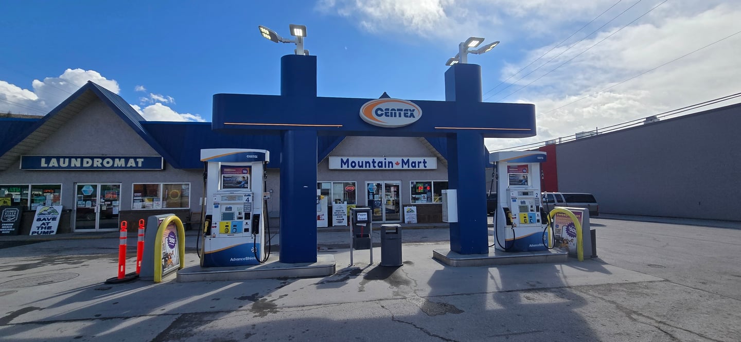 Exterior of Mountain Mart, a view of their gas pumps with the shop and convenience store behind it.