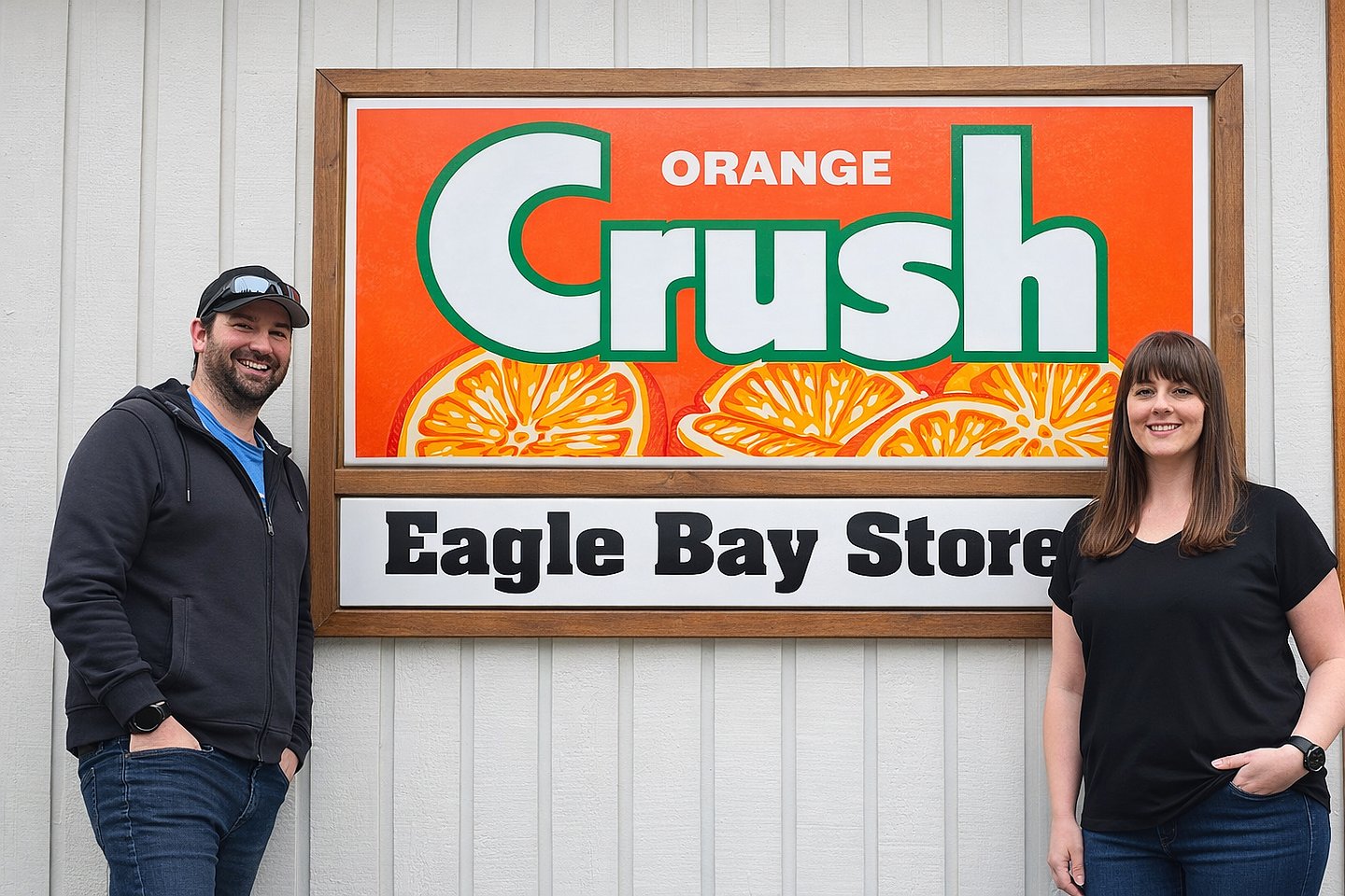 Eagle Bay Store Owners Brittany and Dave Huston in front of their sign that features an ad for Orange Crush
