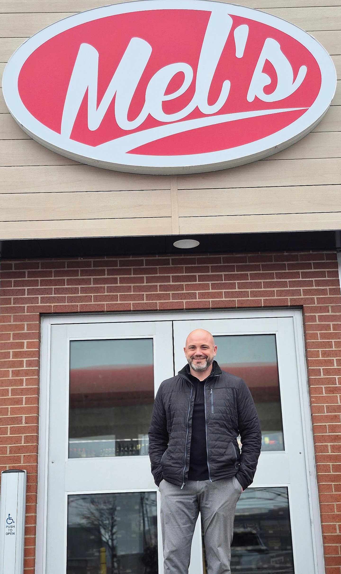 Unnamed owner stands in front of Mel's convenience store.