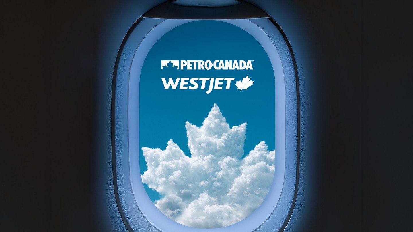 View out of an airplane window focused on a cloud shaped like Petro Canada logo below WestJet logo