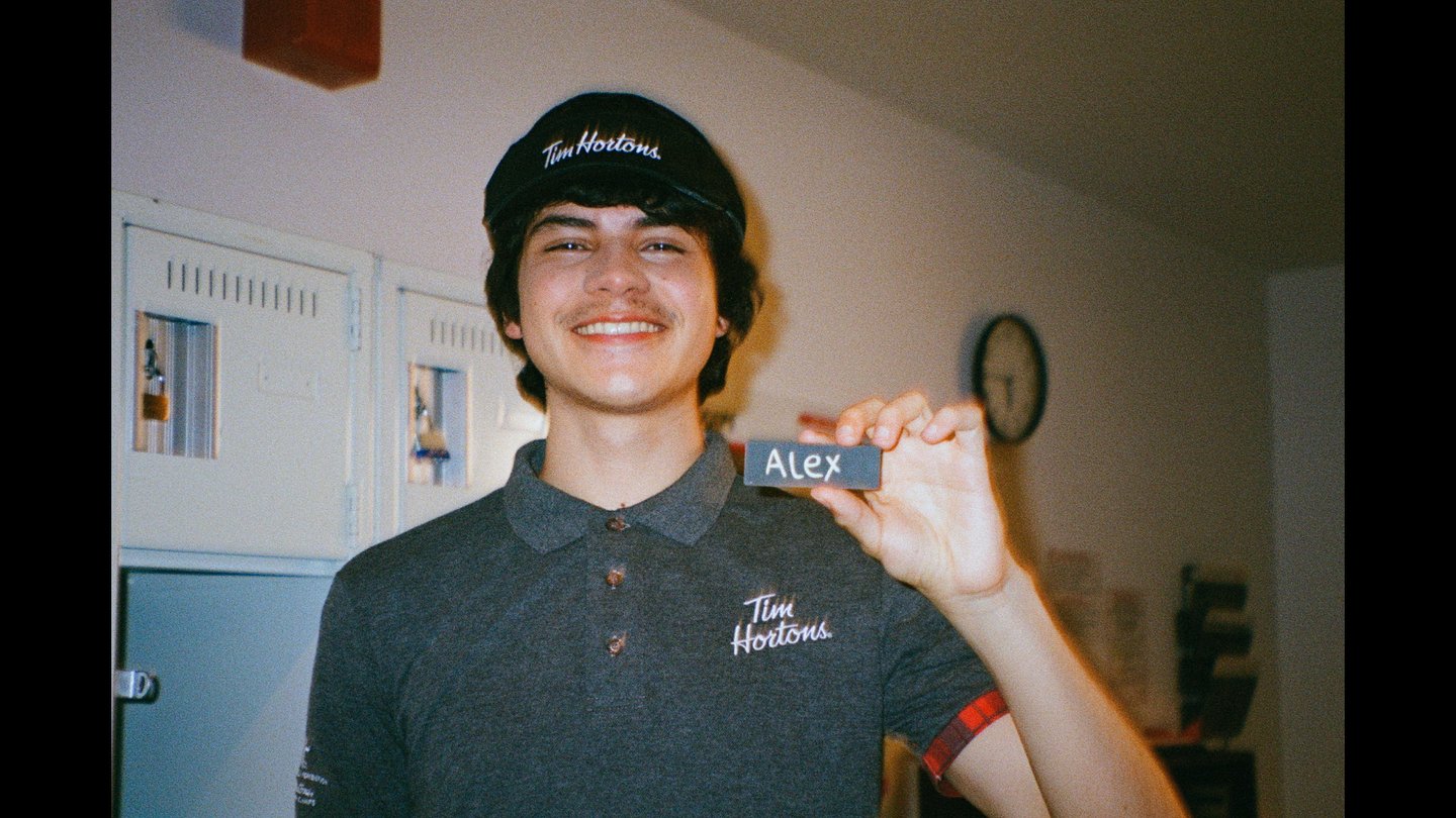 Unnamed youth in Tim Hortons uniform holds up his name tag