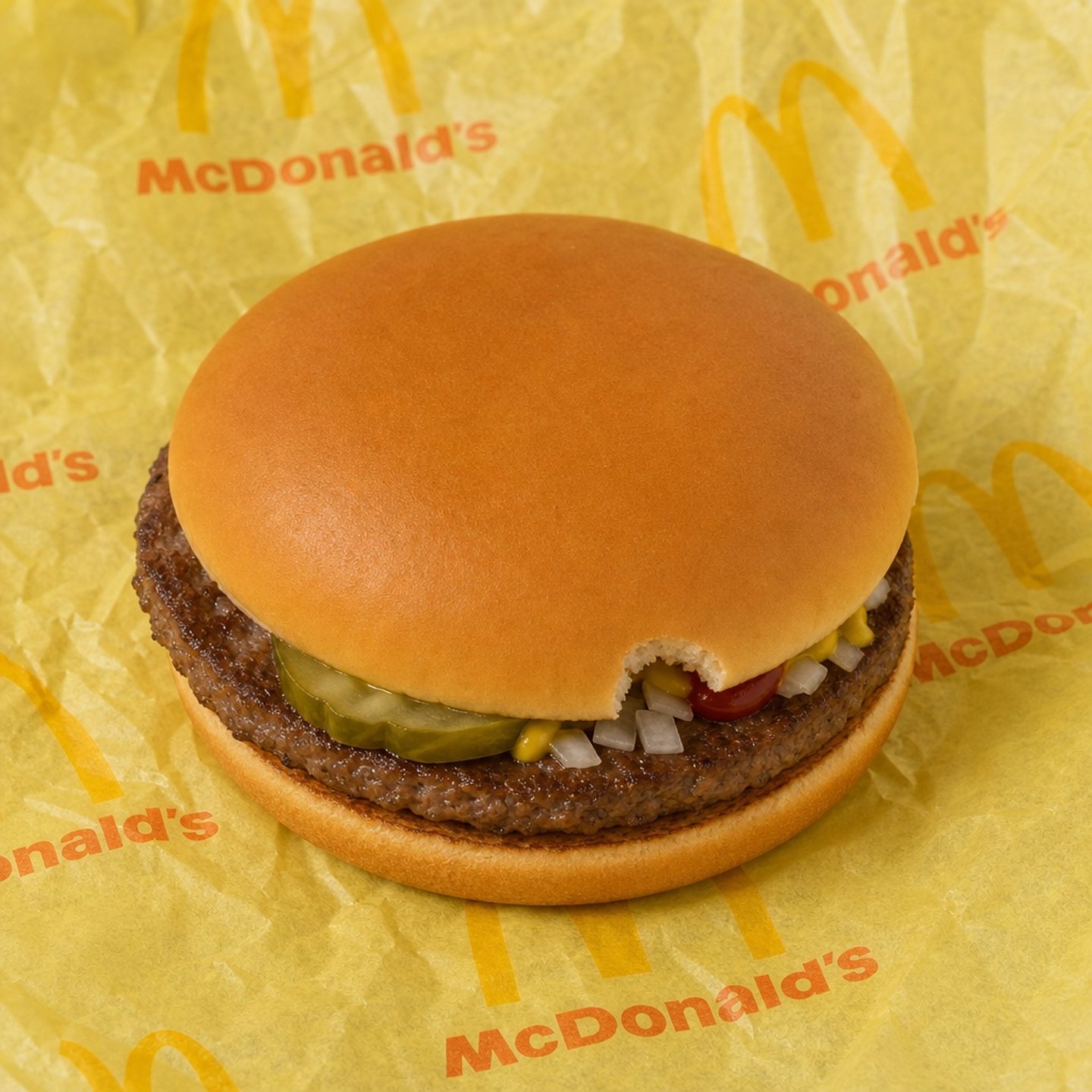 A hamburger with a tiny bite taken out of its bun