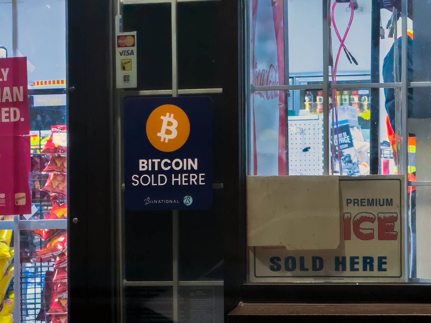 Calgary, Alberta, Canada. Nov 27, 2025. Bitcoin Sold Here Sign Displayed on Convenience Store Window.