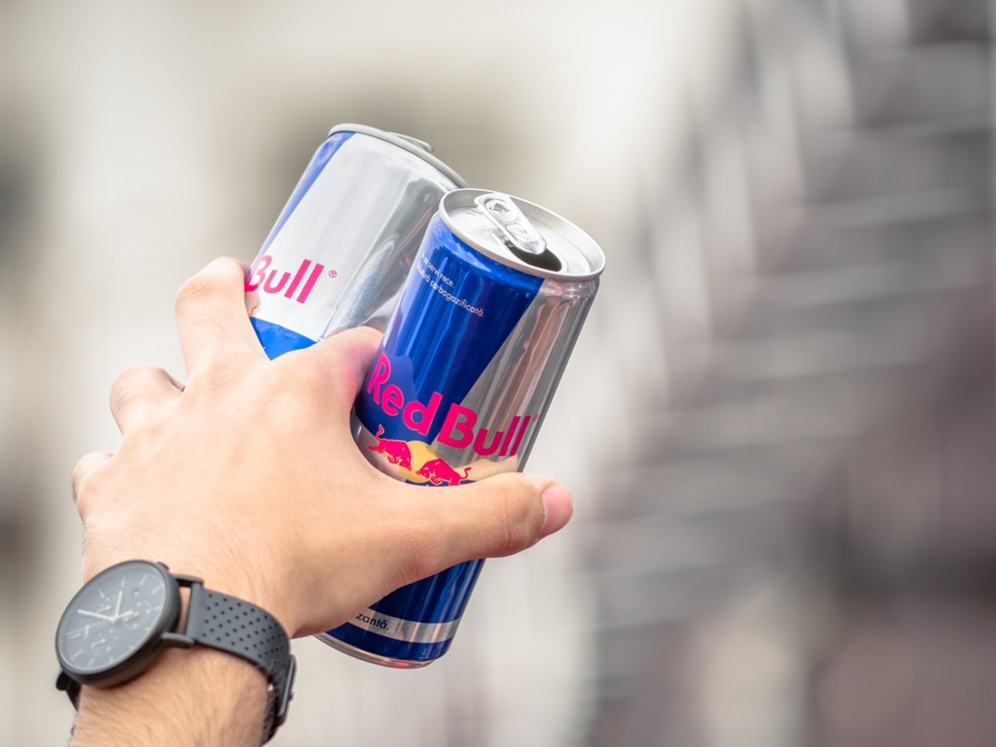 hand holding two cans of Red Bull