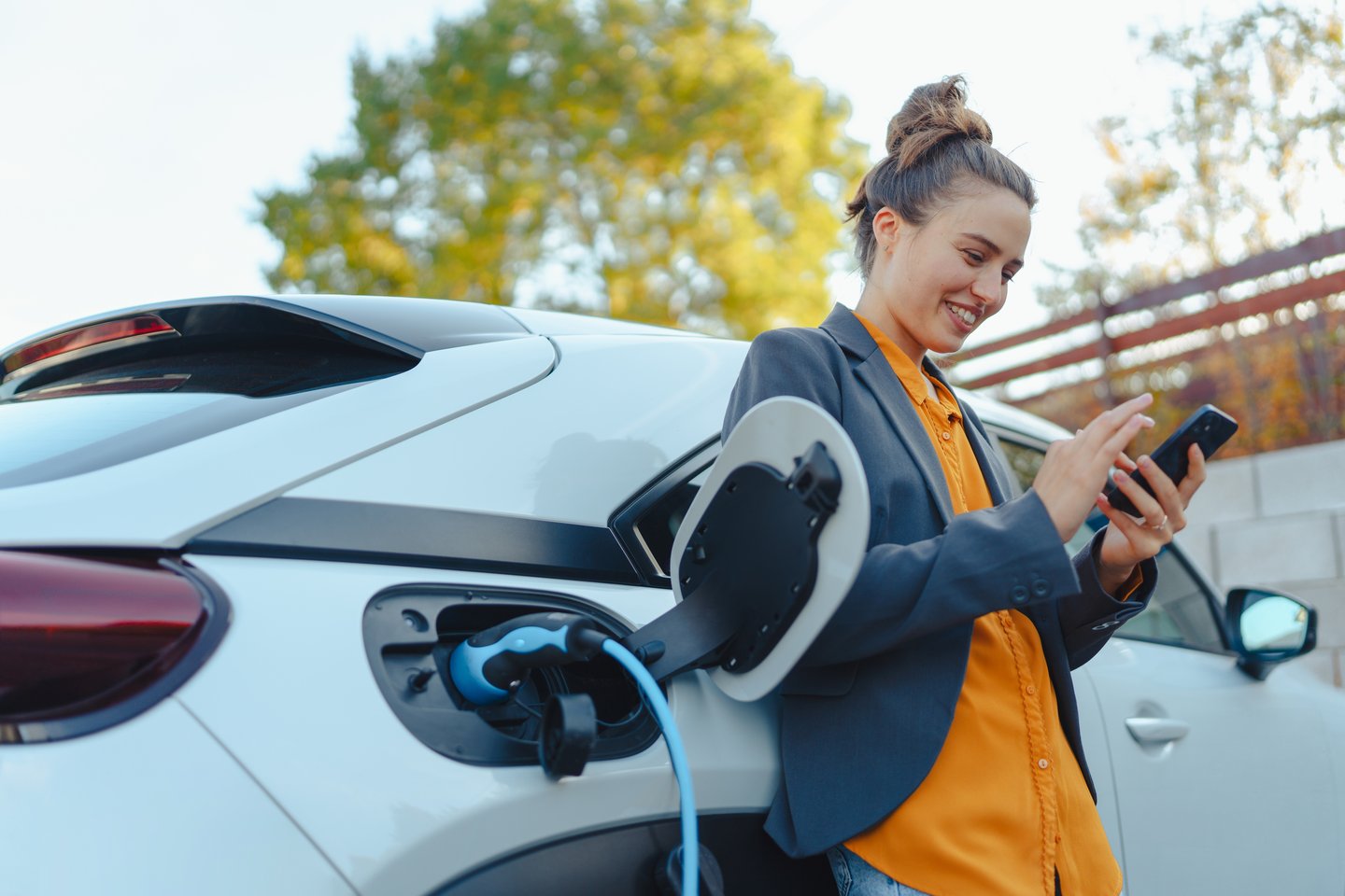 Young women with smartphone charging vehicle