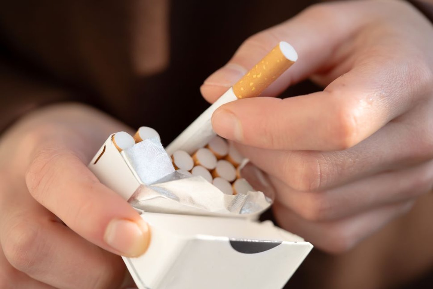 Man pulling a cigarette from a package stock image