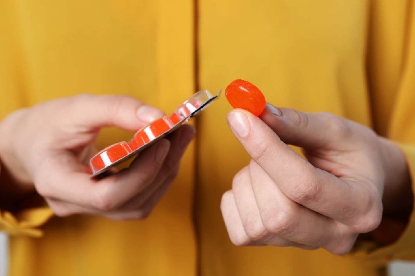 Woman taking throat medication from a package 