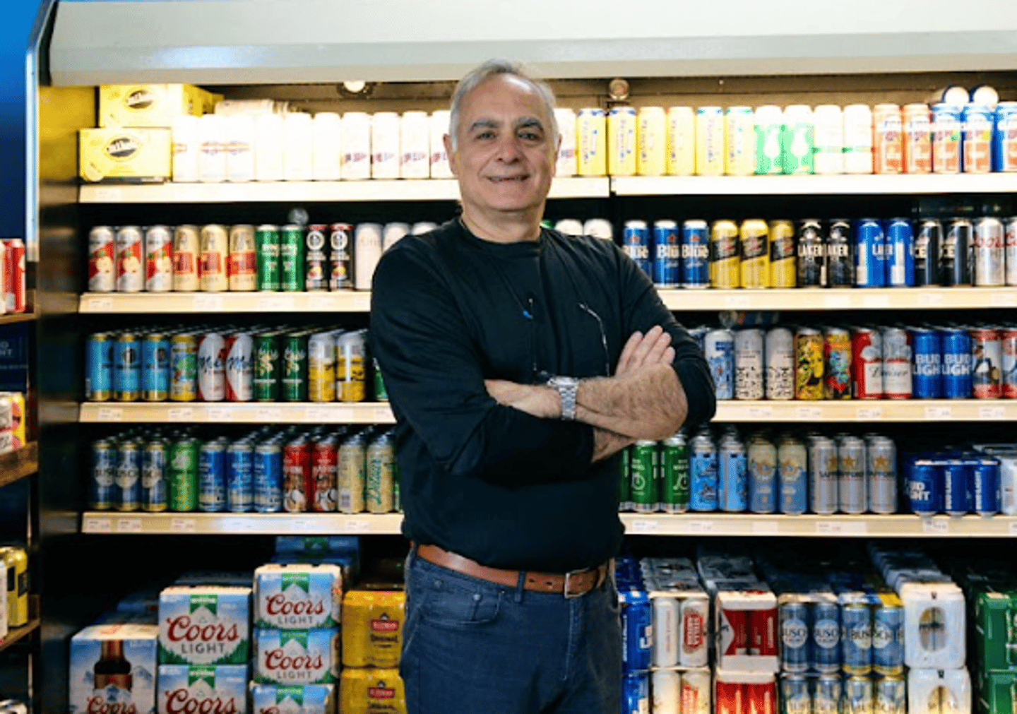 Aziz in front of his beer fridge