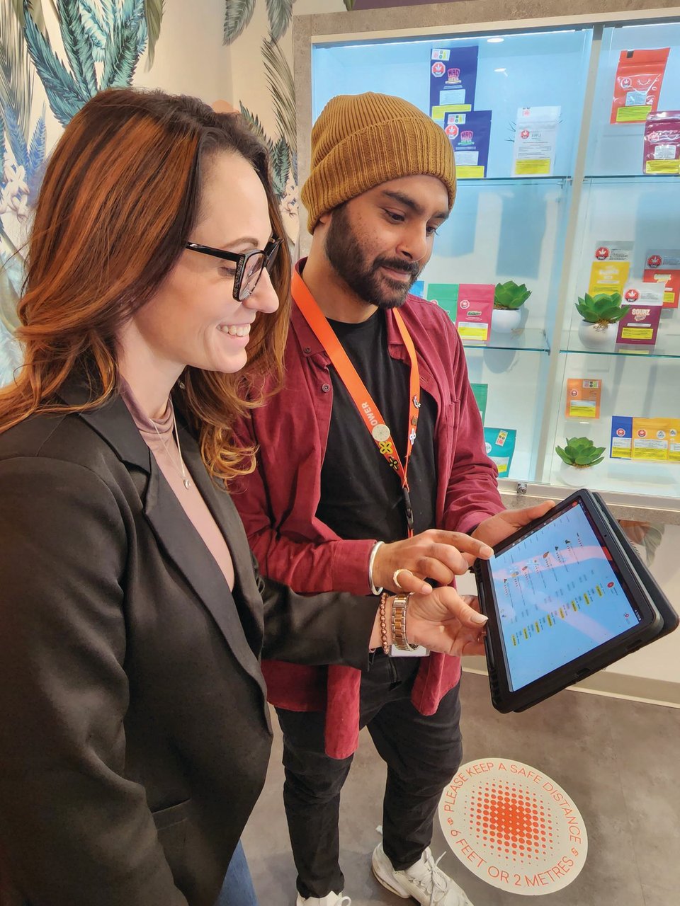 Two people looking at an ipad in the FIre & Flower cannabis store