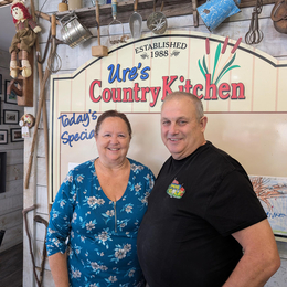 Owners, Laurie and Randy Ure stand in their store, under the shop sign "Ure's Country Kitchen"