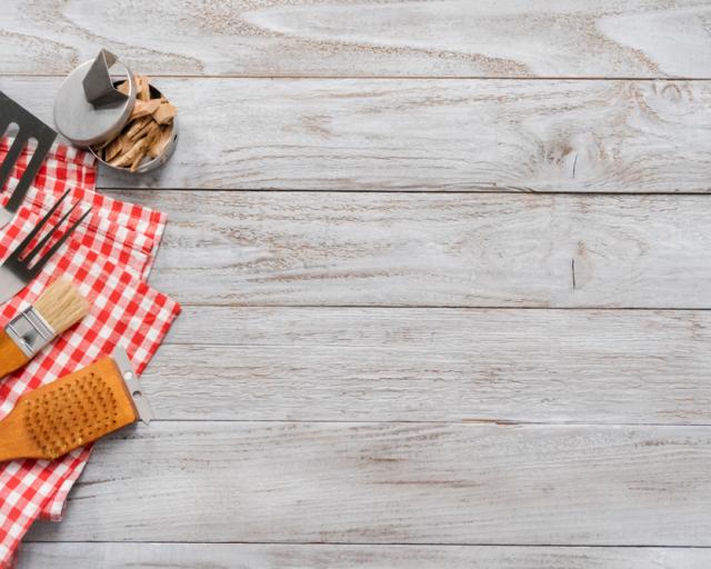 Background with BBQ cooking tools on wood background.