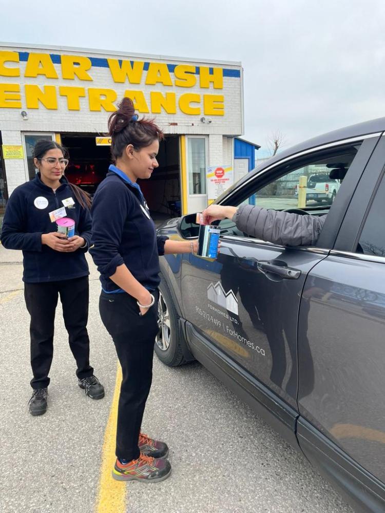 Car wash employee collects donations from a customers car. 