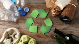Recycling symbol and different garbage on wooden background, top view