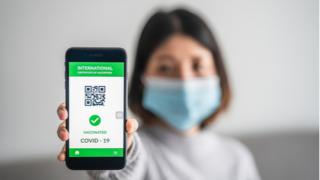 Women holding vaccine passport on cell phone