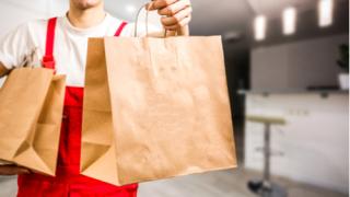 Diverse of paper containers for takeaway food. Delivery man is carrying