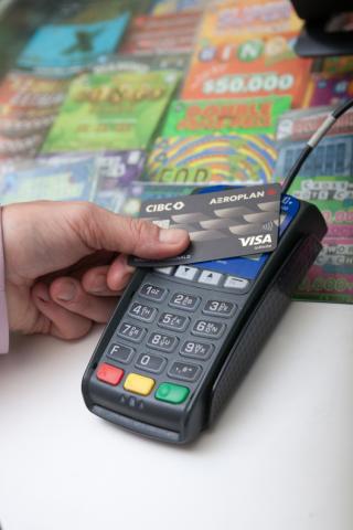 Credit card machine being tapped with lotto tickets in the background