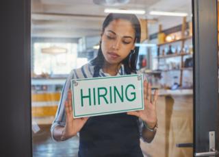 Woman putting up a hiring sign
