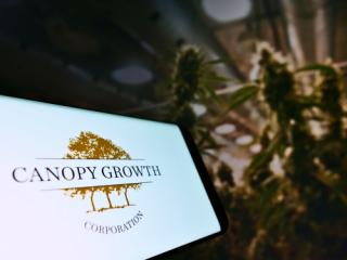Smartphone with logo of Canadian cannabis company Canopy Growth Corporation on screen in front of web page. Focus on centre-right of phone display.