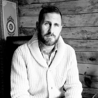 Sean Sportun in a knit cable sweater, with beard, looking into the camera - black and white shot