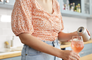 woman pouring rose from can into glass