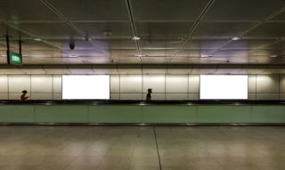 Edited visual for advertising billboard display: Pedestrians walking on moving walkway / travelator in train station. Blank billboards advertising space for mock up purpose; OOH ad placement.