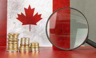 Magnifying glass and coins in front of Canada flag, country economy concept