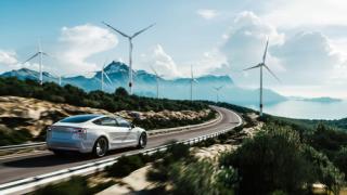 Electric car drive on the wind turbines background. Car drives along a mountain road. Electric car driving along windmills farm. Alternative energy for cars. Car and wind turbines farm. 3d render