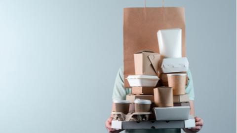 Holding various take-out food containers, pizza box, coffee cups in holder and paper bag, close-up.