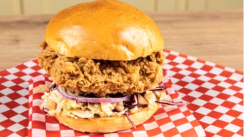 a plant based imitation chicken burger on red checkered paper