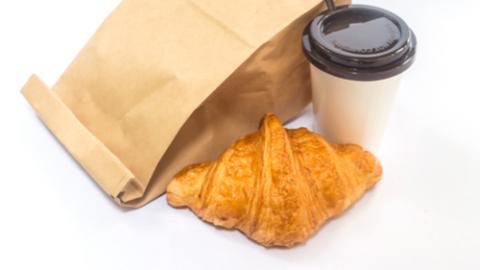 Croissant, coffee and a paper bag - take out breakfast