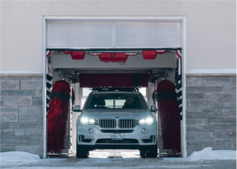 white BMW exiting via car wash door in the winter
