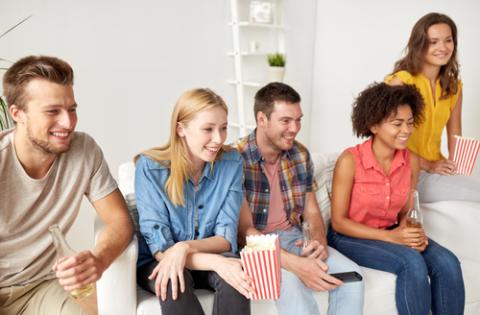 friendship, junk food, people and entertainment concept - happy friends with popcorn and beer watching tv at home