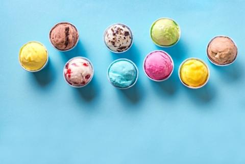 Various ice creams or gelato on blue background, copy space. Frozen yogurt in small paper cups - healthy summer dessert.