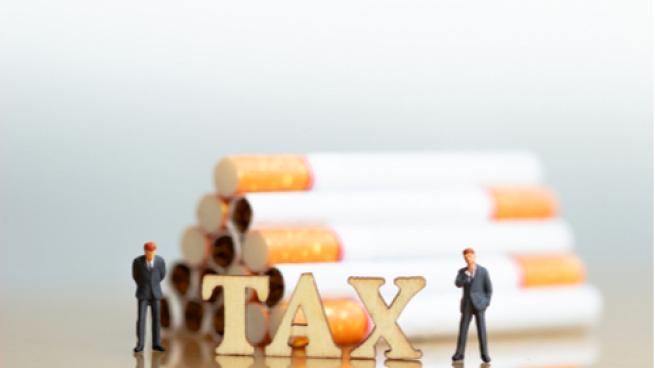 Cigarettes and wood block word TAX on white background. Cigarettes and TAX concept. 