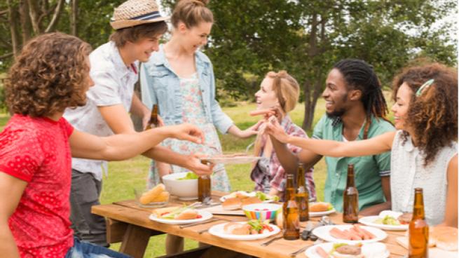 Happy friends in the park having lunch on a sunny day