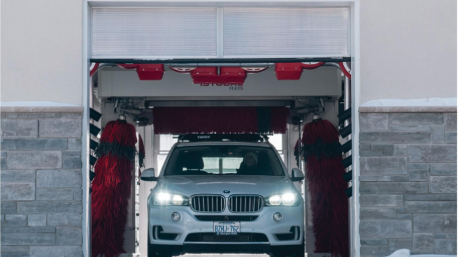 white BMW exiting via car wash door in the winter 
