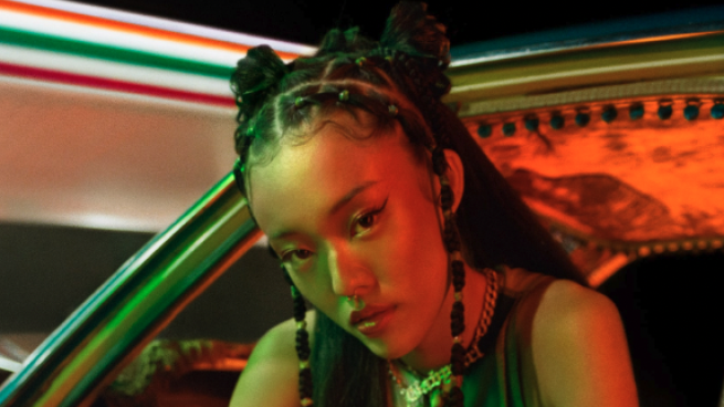 Black Gen Z woman sitting in a car outside 7-Eleven looking into the camera