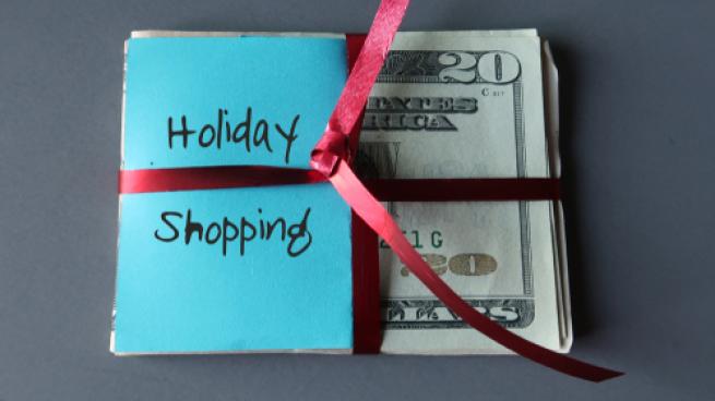 stack of american cash with a bow on it, sticky note that reads holiday shopping