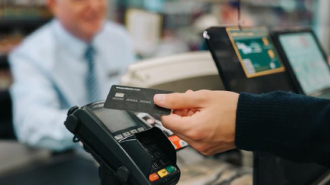 Close-up of a unrecognisable person using credit card to pay at grocery store. Customer making a payment for the purchase using his nfc card at supermarket.
