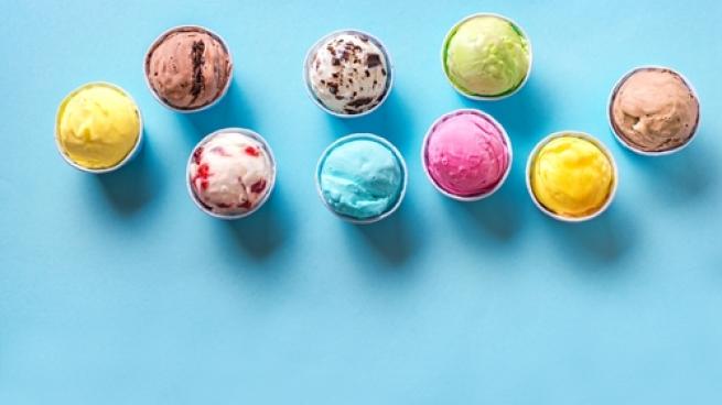 Various ice creams or gelato on blue background, copy space. Frozen yogurt in small paper cups - healthy summer dessert.